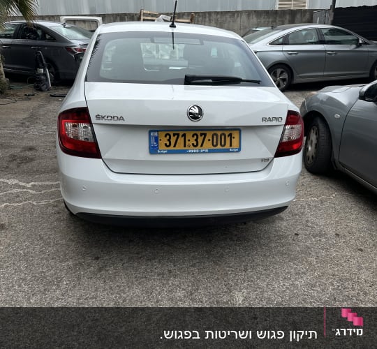 מכונית לבנה חונה בחניון עם לוחית רישוי ישראלית